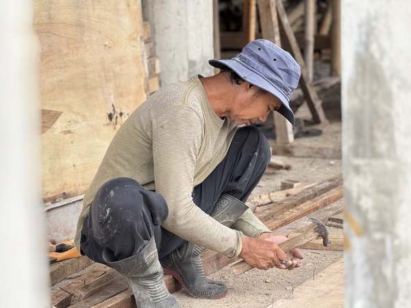 Tukang mengerjakan rangka kayu di lokasi pembangunan